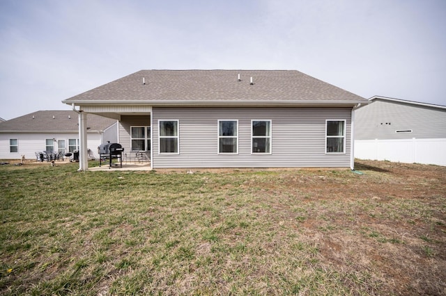 rear view of house with a patio, a lawn, fence, and roof with shingles