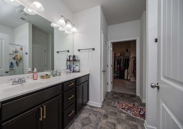 full bath with double vanity, stone finish floor, a sink, and visible vents