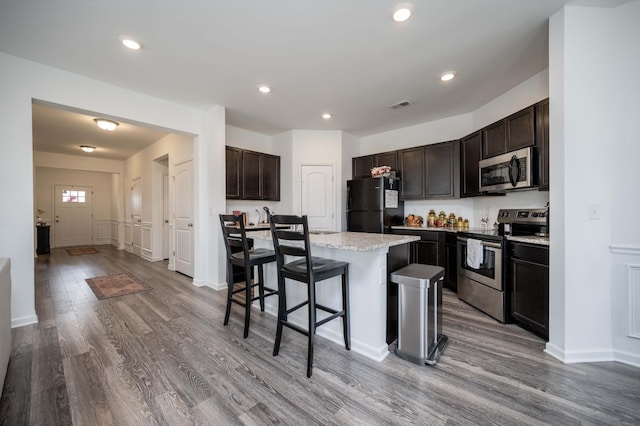 kitchen featuring stainless steel appliances, a breakfast bar, visible vents, and wood finished floors