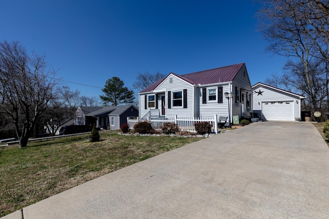 view of front of property featuring a garage, driveway, metal roof, an outdoor structure, and a front yard