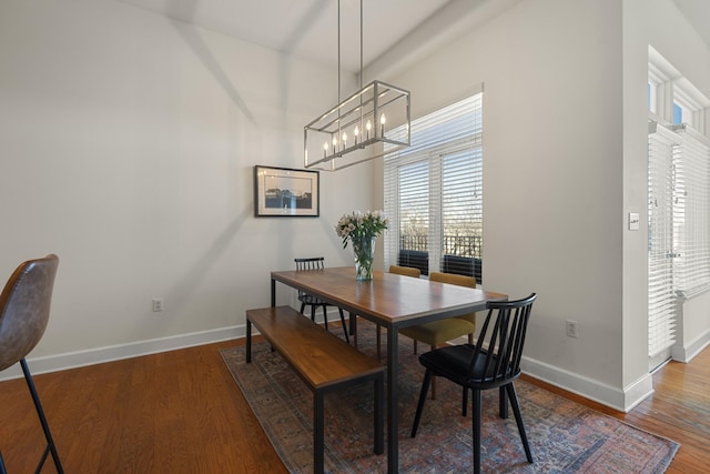 dining space with baseboards, a chandelier, and wood finished floors