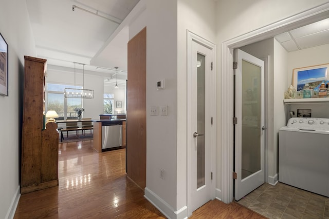 hall featuring a notable chandelier, baseboards, washer / clothes dryer, and wood finished floors