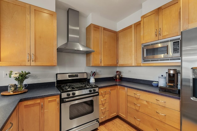 kitchen featuring appliances with stainless steel finishes, dark countertops, light wood-style flooring, and wall chimney exhaust hood