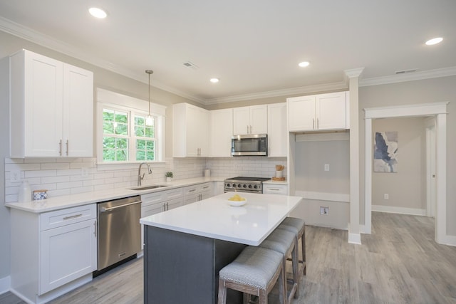 kitchen featuring appliances with stainless steel finishes, a sink, a breakfast bar, and white cabinets