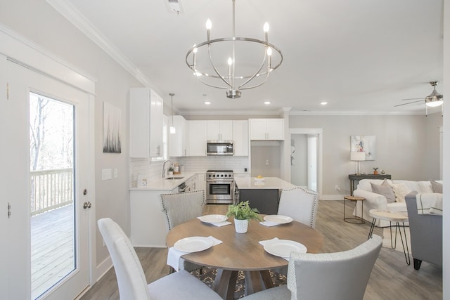 dining room featuring baseboards, light wood finished floors, ceiling fan with notable chandelier, and crown molding