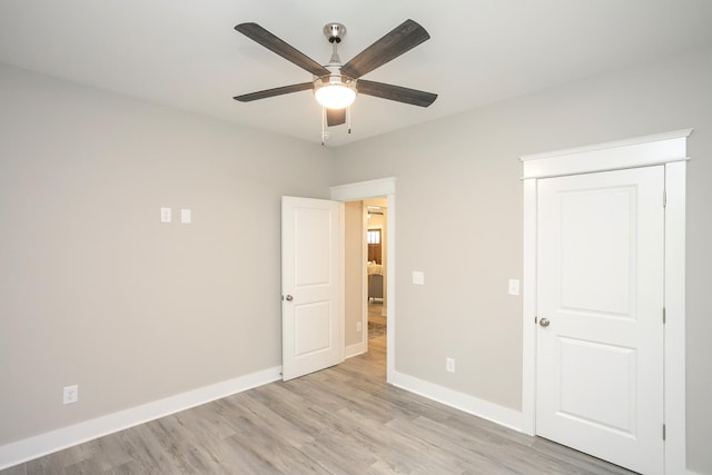 unfurnished bedroom featuring ceiling fan, a closet, light wood-style flooring, and baseboards