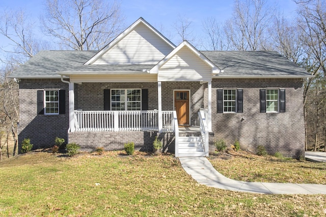 view of front facade featuring a porch, a front yard, brick siding, and roof with shingles