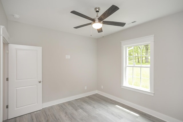 spare room featuring light wood-type flooring, visible vents, baseboards, and a ceiling fan