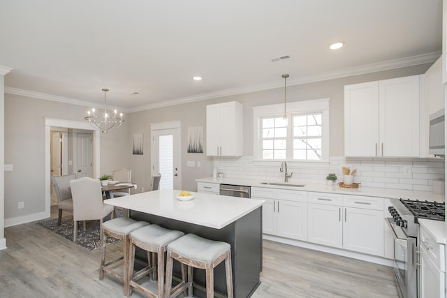 kitchen featuring a breakfast bar area, stainless steel appliances, a sink, visible vents, and white cabinetry