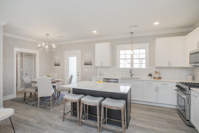 kitchen featuring visible vents, appliances with stainless steel finishes, a kitchen breakfast bar, a sink, and backsplash