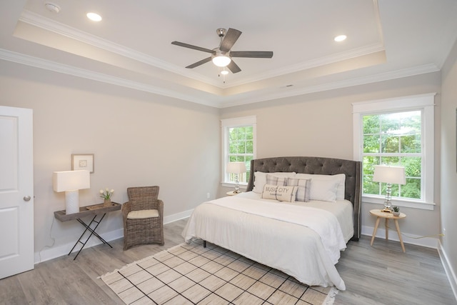 bedroom with recessed lighting, a raised ceiling, light wood-style floors, ornamental molding, and baseboards