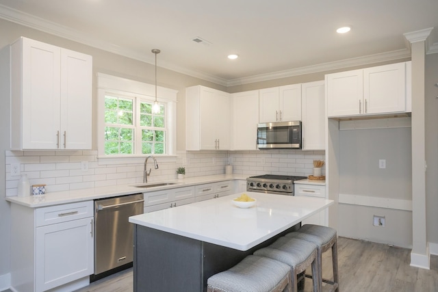 kitchen featuring visible vents, appliances with stainless steel finishes, a kitchen breakfast bar, ornamental molding, and a sink