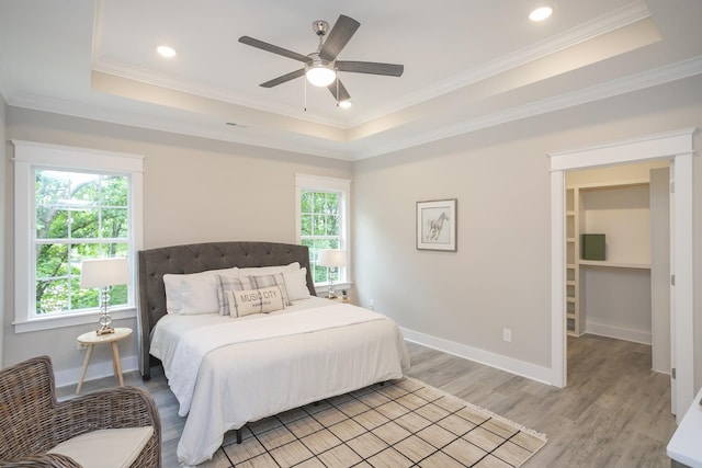 bedroom featuring ornamental molding, a raised ceiling, baseboards, and light wood finished floors