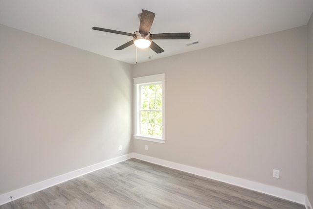 unfurnished room featuring a ceiling fan, wood finished floors, visible vents, and baseboards