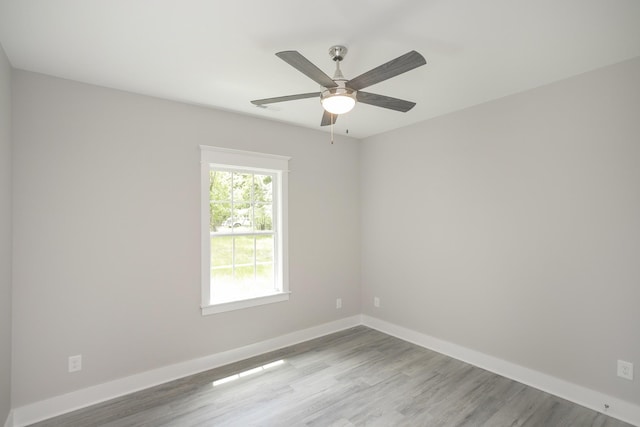 empty room featuring a ceiling fan, baseboards, and wood finished floors