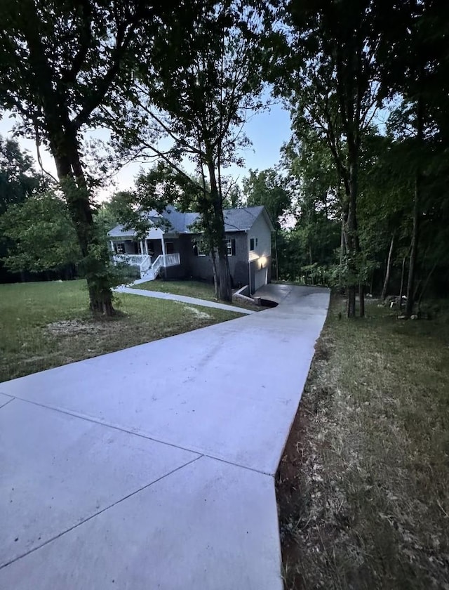 exterior space featuring an attached garage, a lawn, a porch, and concrete driveway