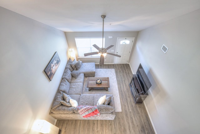 living room with ceiling fan, baseboards, and wood finished floors