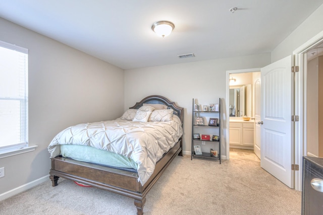 bedroom featuring light carpet, visible vents, baseboards, and ensuite bathroom