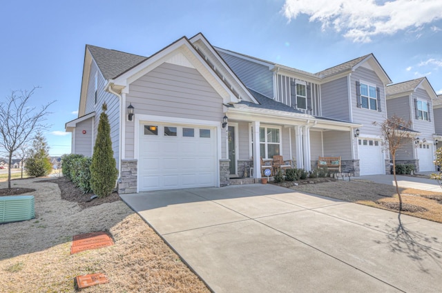 craftsman inspired home featuring covered porch, concrete driveway, stone siding, and a garage