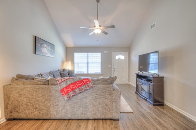 living room featuring baseboards, visible vents, ceiling fan, wood finished floors, and high vaulted ceiling