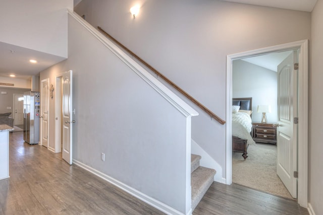 stairway featuring recessed lighting, wood finished floors, and baseboards