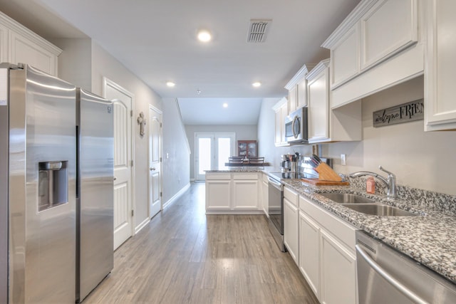 kitchen with visible vents, light wood-style flooring, appliances with stainless steel finishes, a sink, and a peninsula