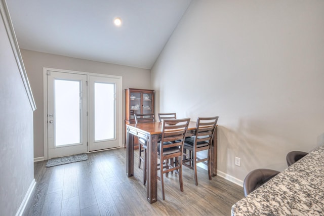 dining area with lofted ceiling, baseboards, and wood finished floors