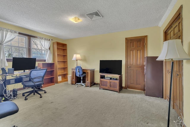 office space with visible vents, light carpet, and a textured ceiling