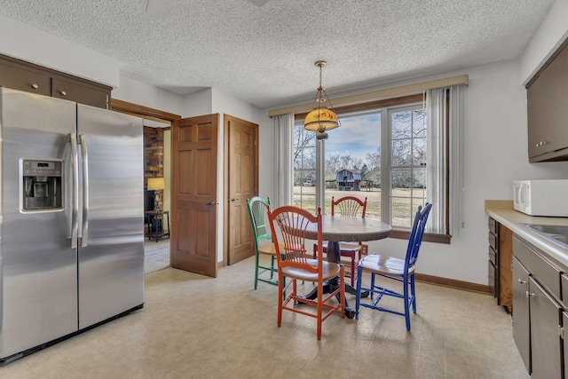 dining space featuring light floors, a textured ceiling, and baseboards