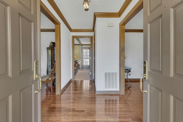 entryway with ornamental molding, light wood-type flooring, visible vents, and baseboards