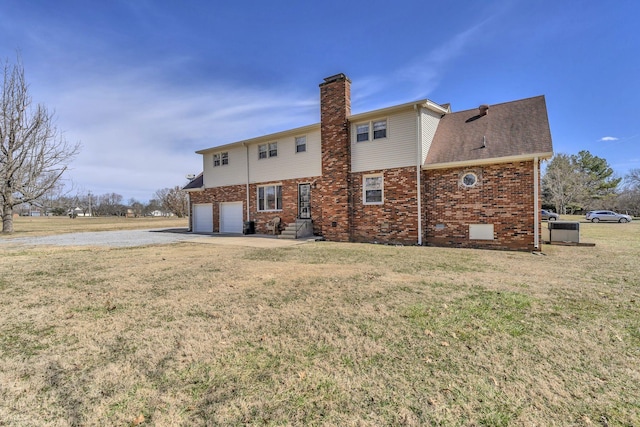 rear view of property with a garage, brick siding, roof with shingles, a lawn, and a chimney