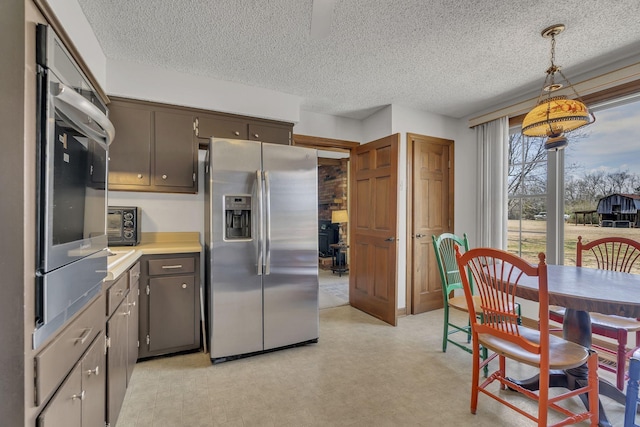 kitchen featuring a textured ceiling, hanging light fixtures, light countertops, stainless steel refrigerator with ice dispenser, and light floors