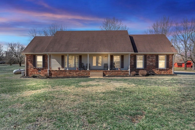 single story home with covered porch, brick siding, and a front yard