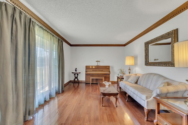 living area featuring baseboards, crown molding, a textured ceiling, and light wood finished floors