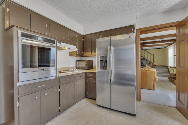 kitchen featuring dark brown cabinetry, stainless steel appliances, a textured ceiling, light countertops, and under cabinet range hood