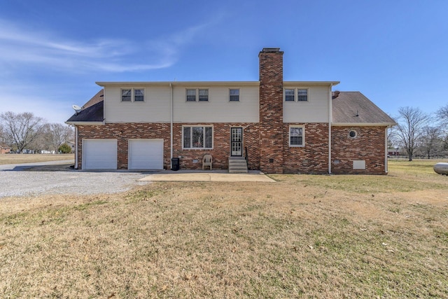 back of property featuring a yard, driveway, brick siding, and a chimney