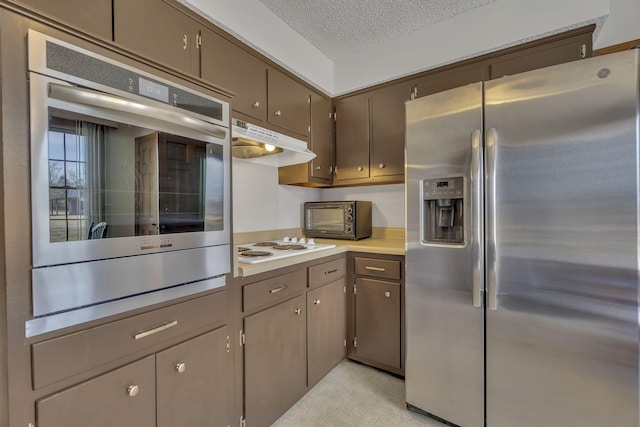 kitchen featuring a toaster, appliances with stainless steel finishes, light countertops, a textured ceiling, and under cabinet range hood