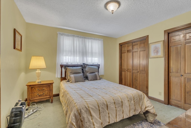 bedroom featuring baseboards, a textured ceiling, and light colored carpet