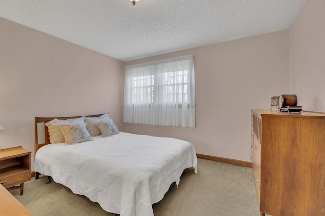 bedroom featuring light carpet, a textured ceiling, and baseboards