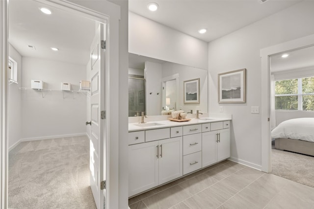 bathroom featuring double vanity, a shower stall, baseboards, and a sink