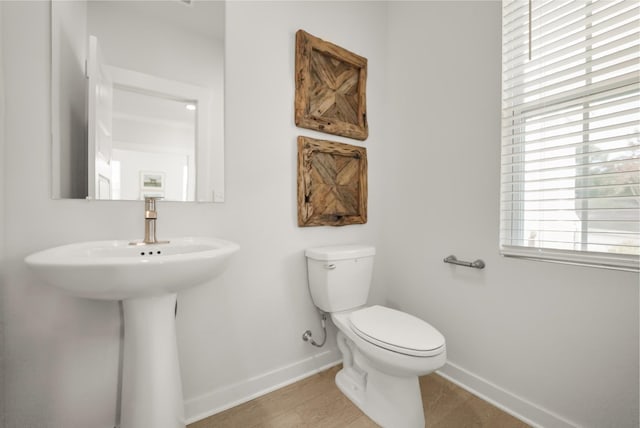 bathroom with toilet, baseboards, and wood finished floors