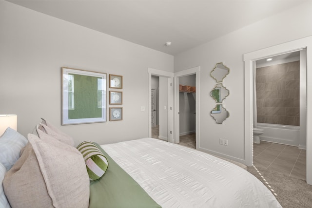 bedroom with baseboards, connected bathroom, tile patterned flooring, a walk in closet, and a closet