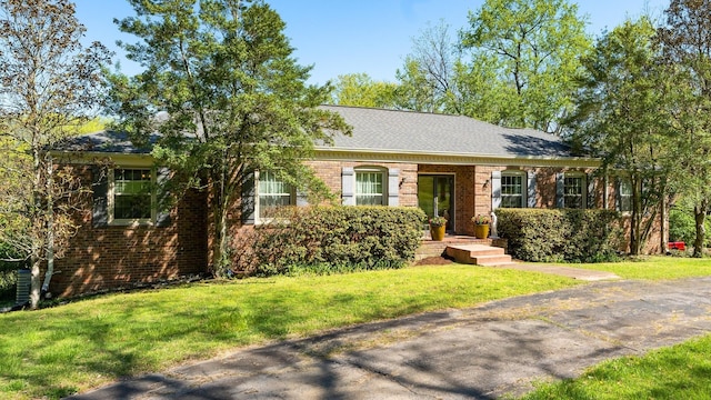 ranch-style house with a front yard, brick siding, and roof with shingles