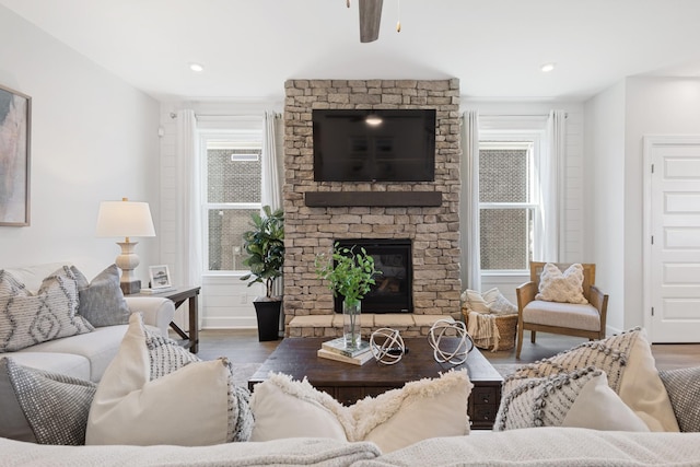 living area featuring recessed lighting, wood finished floors, and a stone fireplace