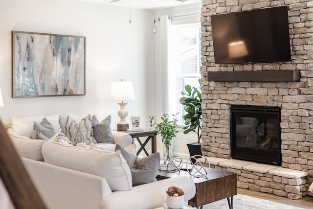 living room with a large fireplace, a healthy amount of sunlight, and wood finished floors