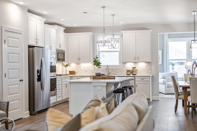 kitchen with stainless steel appliances, a kitchen island, light countertops, and white cabinets