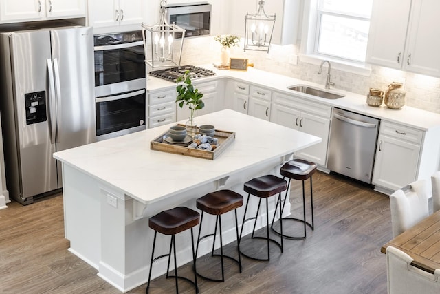 kitchen featuring white cabinetry, appliances with stainless steel finishes, a sink, and wood finished floors