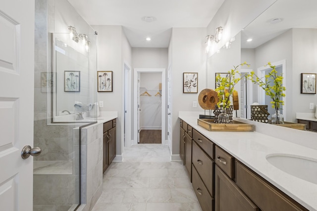 bathroom with vanity, baseboards, marble finish floor, tiled shower, and a walk in closet