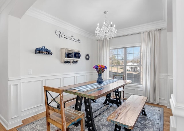 dining room featuring ornamental molding, light wood-type flooring, and a notable chandelier