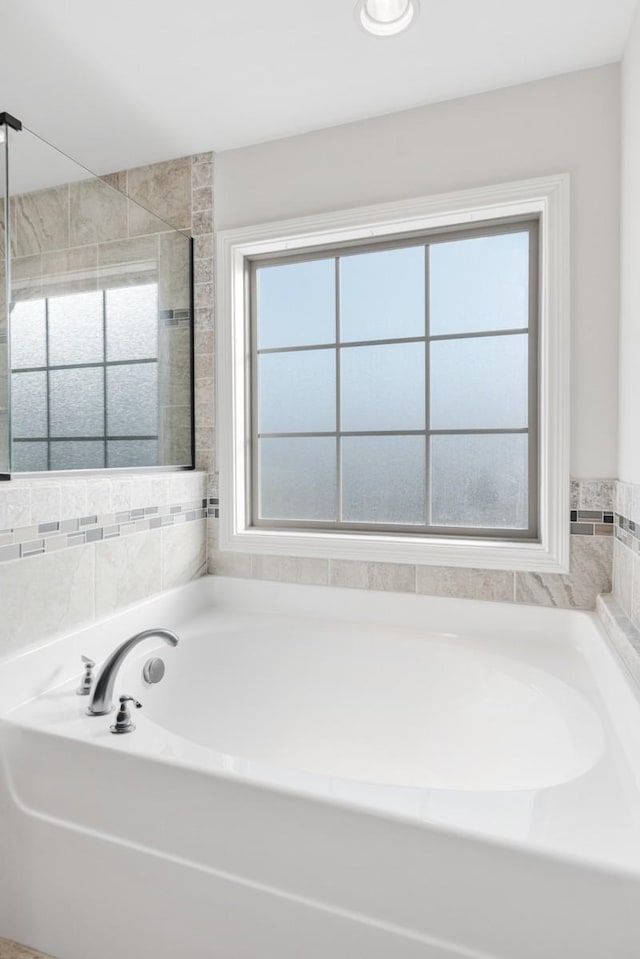 bathroom with a stall shower, a garden tub, and plenty of natural light